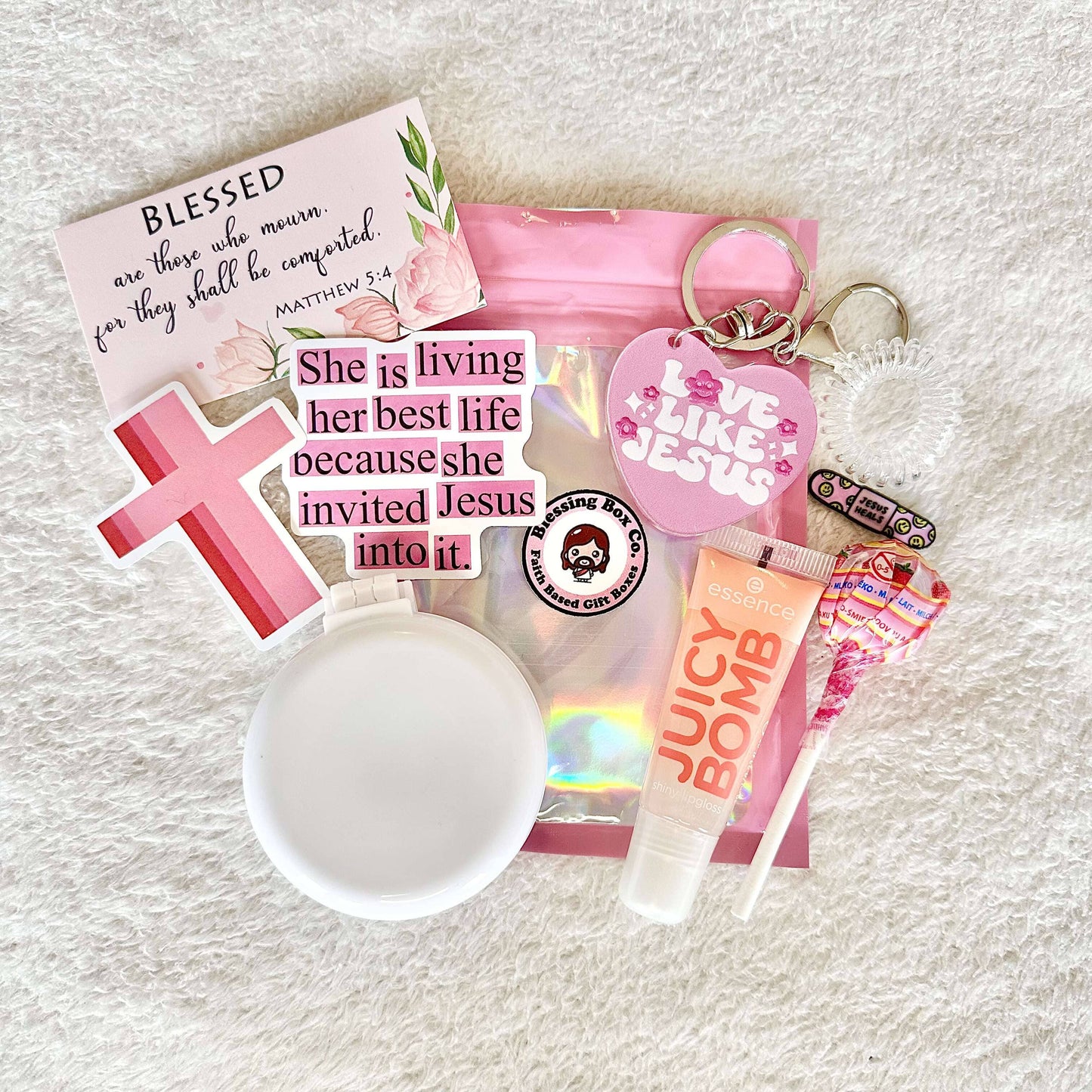 Gift set featuring Christian stickers, sweet treat, inspirational scripture card, essence lipgloss, faith inspired keychain, a mini hair brush, a faith based pin, and a little spiral hair tie
