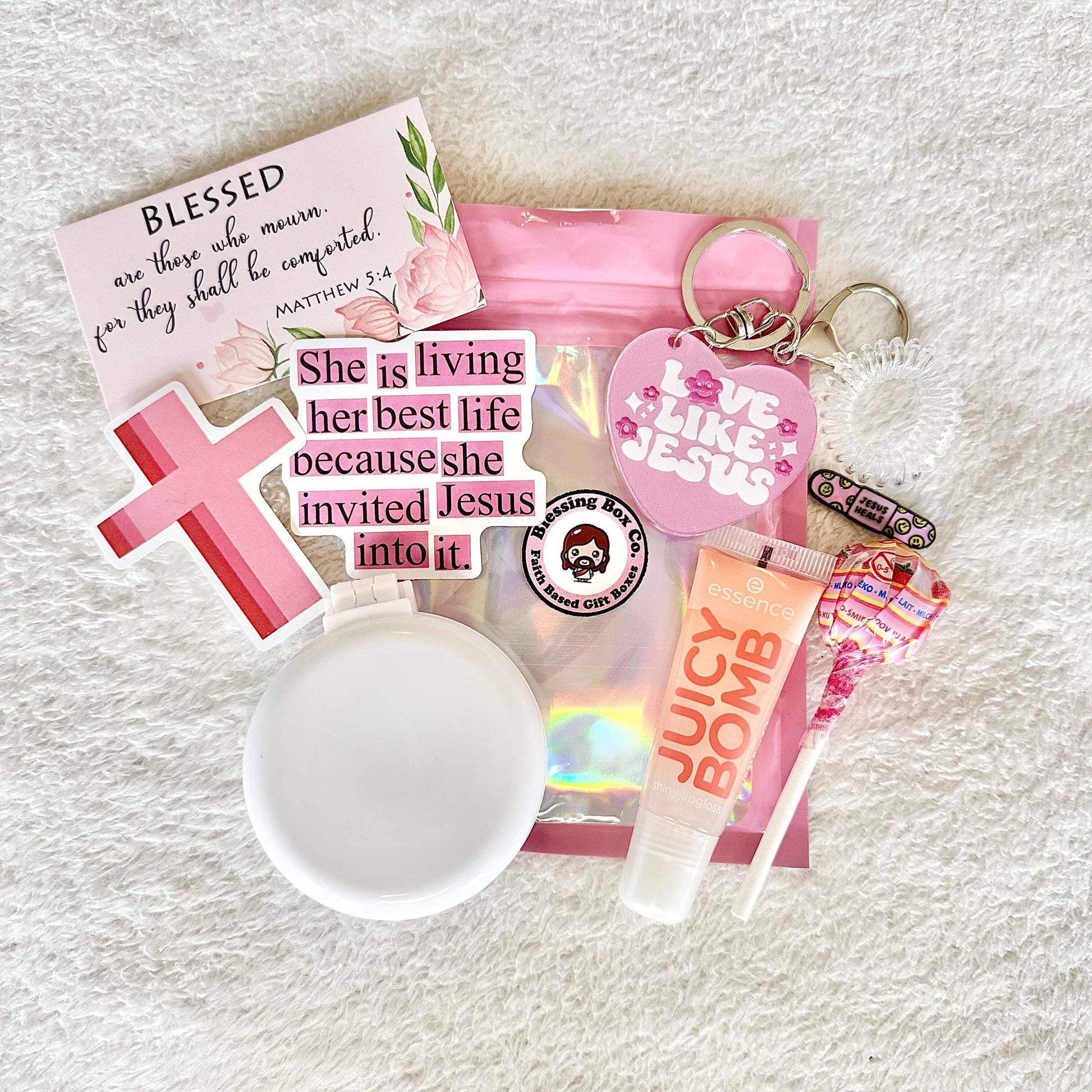 Gift set featuring Christian stickers, sweet treat, inspirational scripture card, essence lipgloss, faith inspired keychain, a mini hair brush, a faith based pin, and a little spiral hair tie